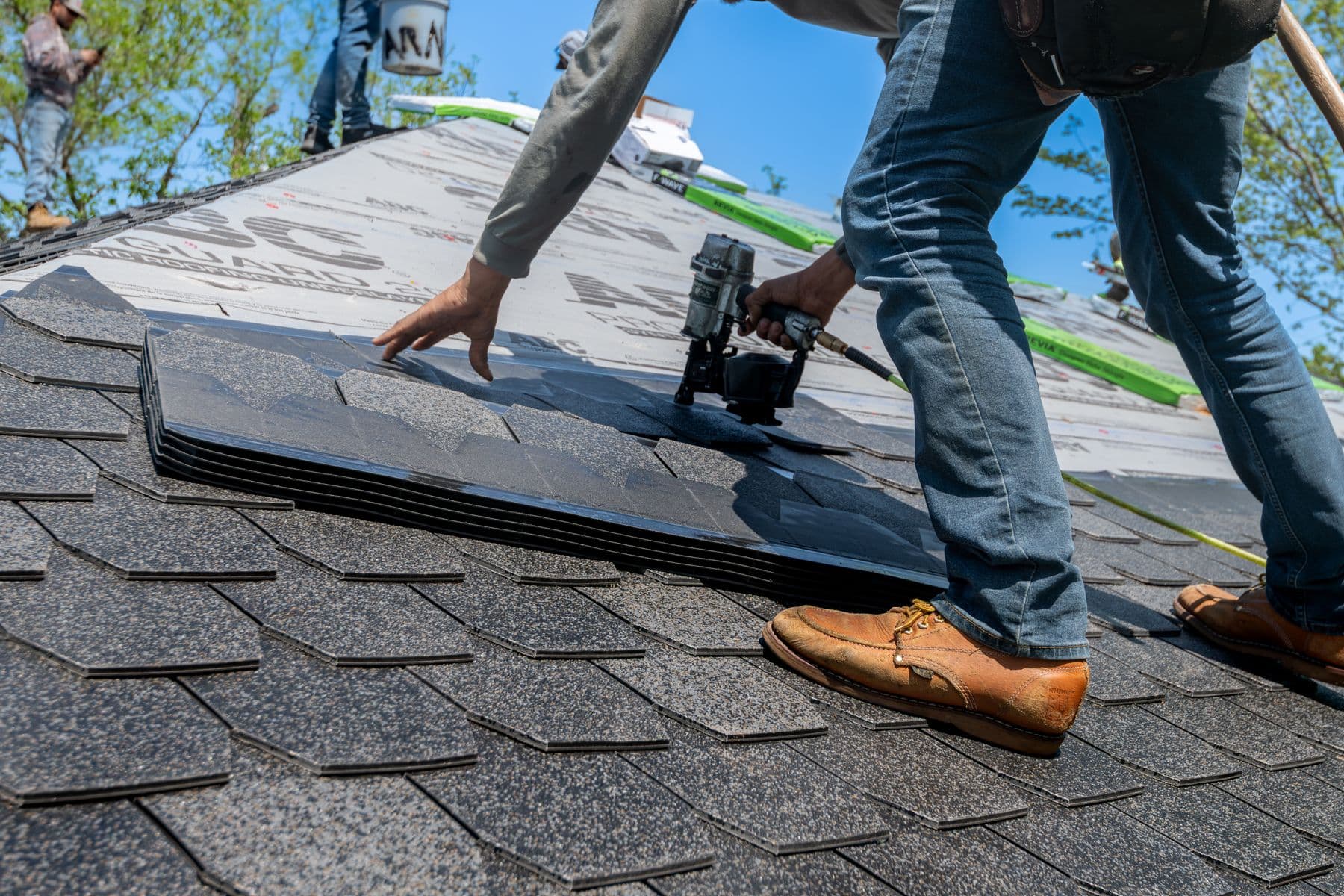 Roofer installing architectural asphalt shingles on a residential roof